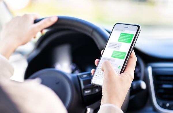 A driver holding a smartphone while operating a vehicle, highlighting the dangerous behaviors behind Alabama distracted driving statistics and the need for legal help following a crash.